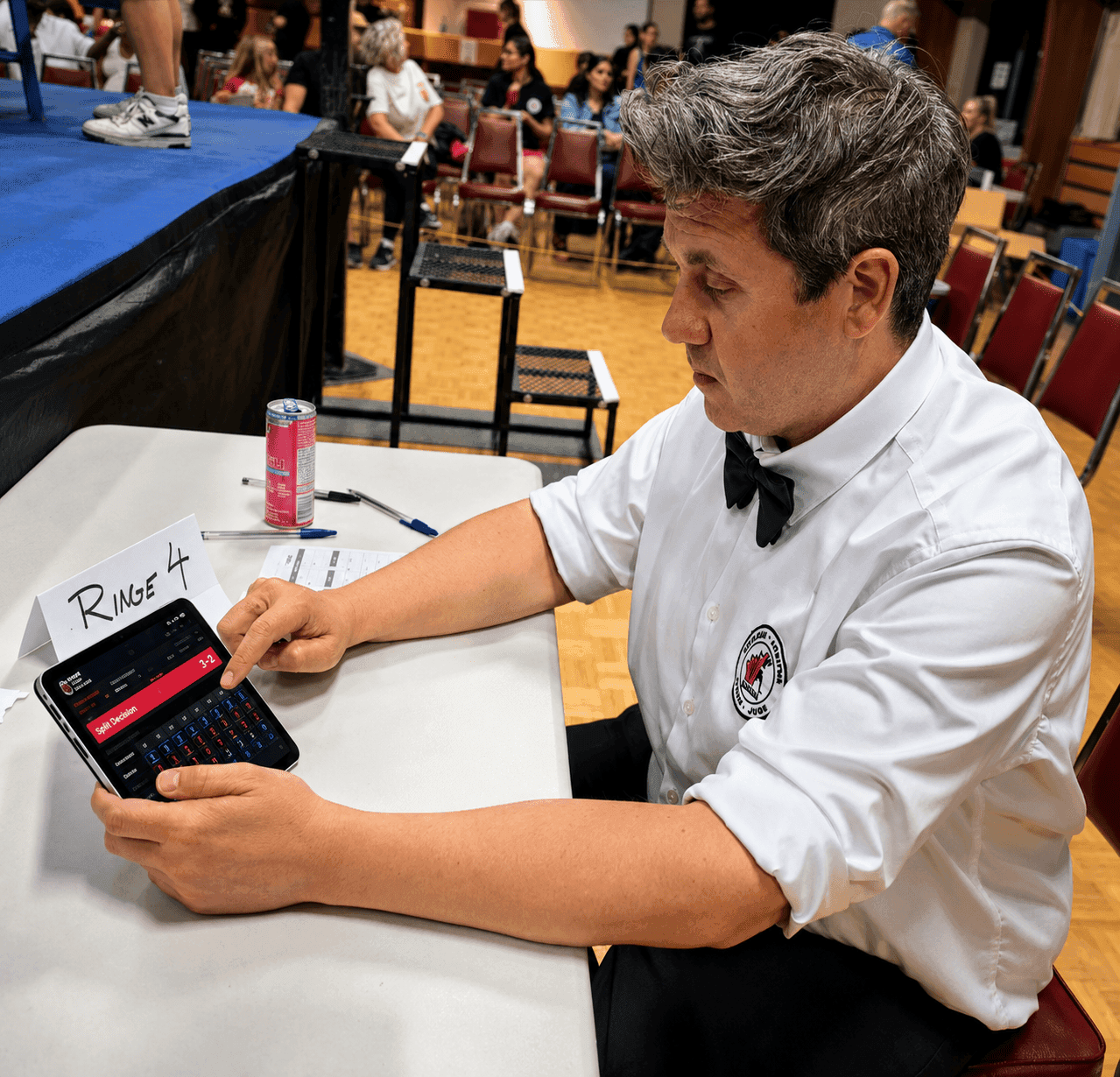 An official reviewing a RingScore result view on a tablet at ringside.